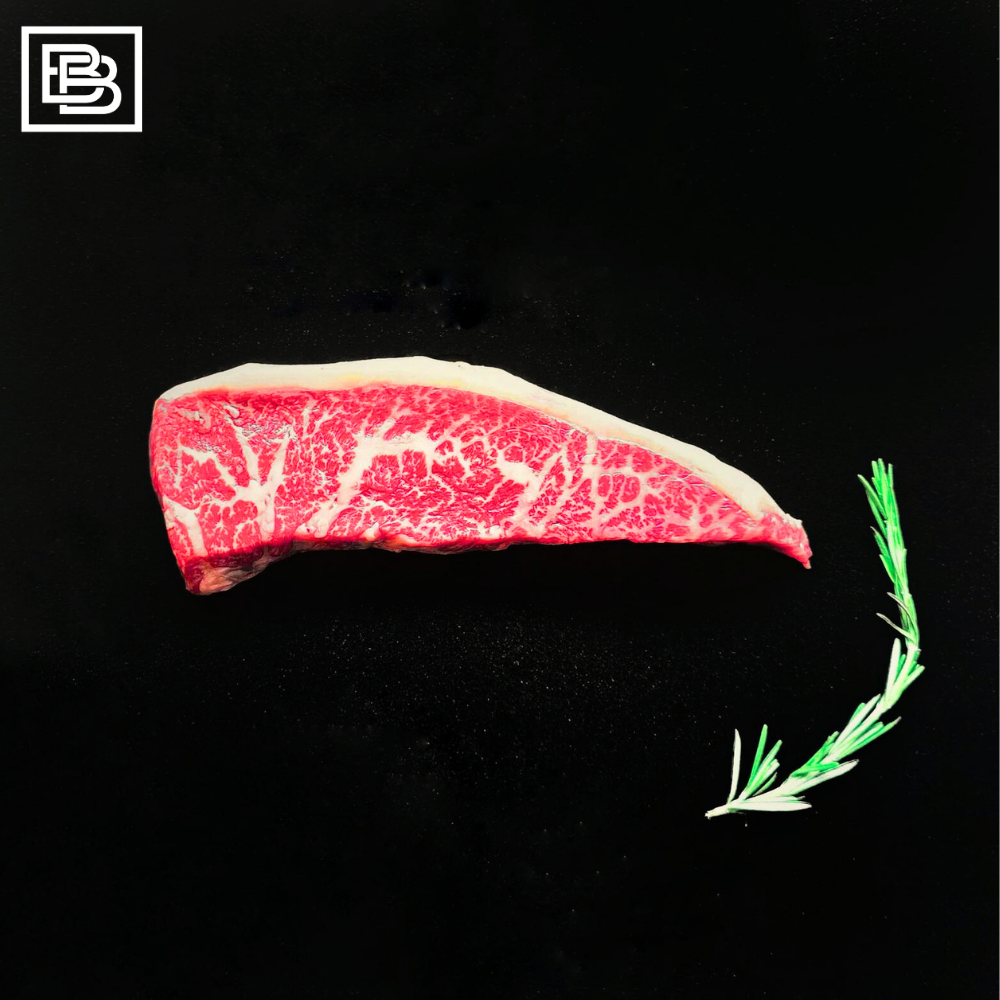 Stone Axe Rump Cap (Picanha) Steak on a black surface with a Rosemary stalk